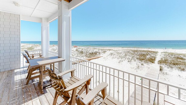 A wooden deck with a table and chairs, overlooking a beach with sand dunes and the ocean. - Spacious beachfront home with Gulf-view decks, boardwalk, & pool (Orange Beach)