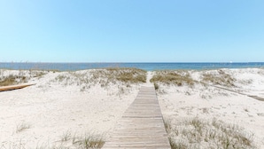 A sandy beach with a wooden boardwalk leading to the ocean. - Spacious beachfront home with Gulf-view decks, boardwalk, & pool (Orange Beach)