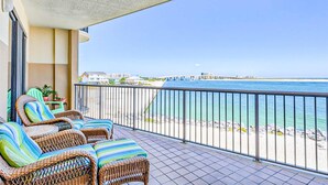 Un balcon doté de meubles en osier et offrant une vue sur la plage.