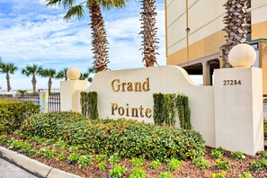 Ein Hotel Eingang mit einem Schild mit der Aufschrift 'Grand Pointe', Palmen und einem gepflegten Garten.