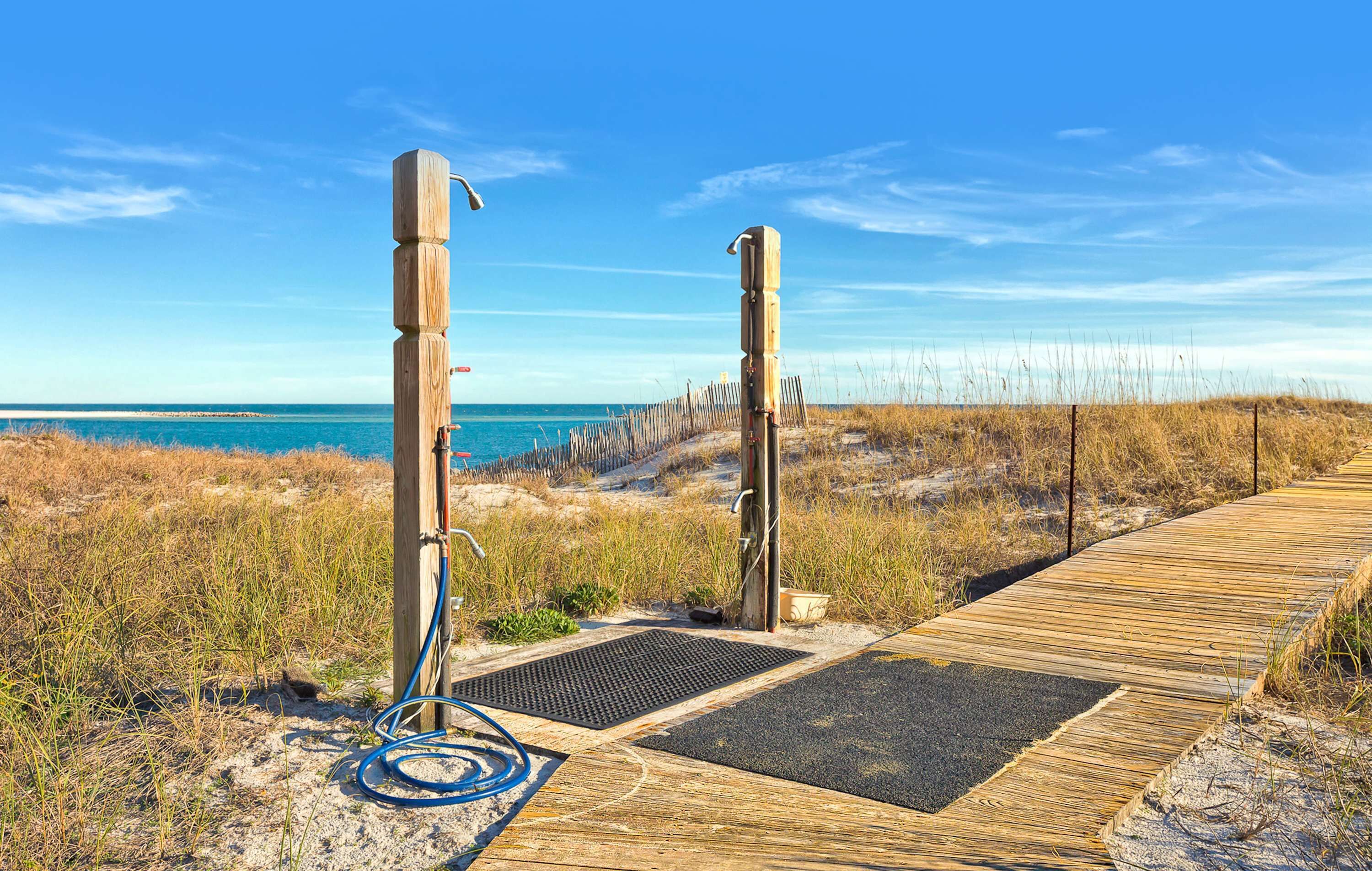 A wooden boardwalk leading to a beach with a clear sky.