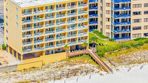 Ein mehrstöckiges Hotel mit Balkonen, Blick auf den Strand und einem Parkplatz.