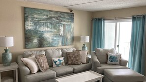 Ein Wohnzimmer mit einem beigen Sofa, einem weißen Couchtisch und einem Bild an der Wand.