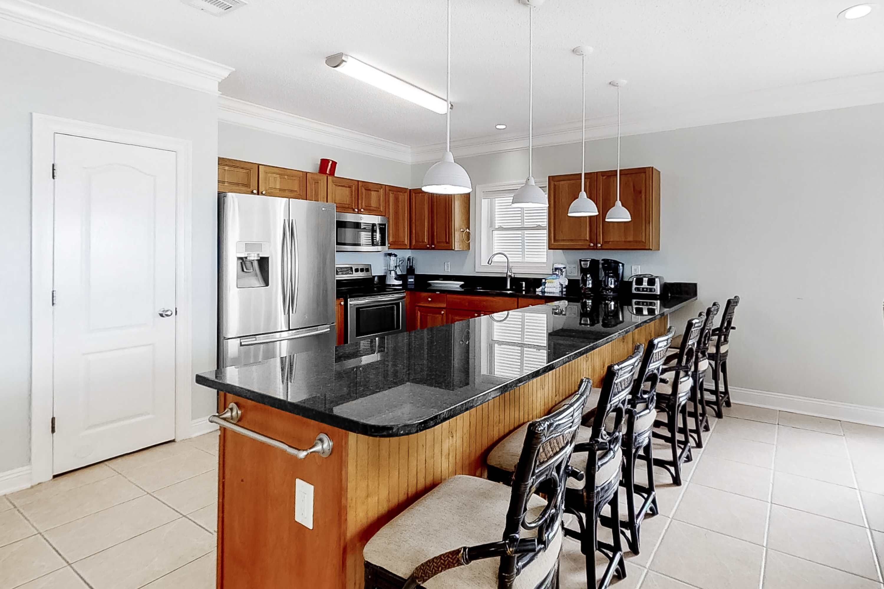 Una cocina moderna con una isla grande, armarios de madera, electrodomésticos de acero inoxidable y taburetes de bar.