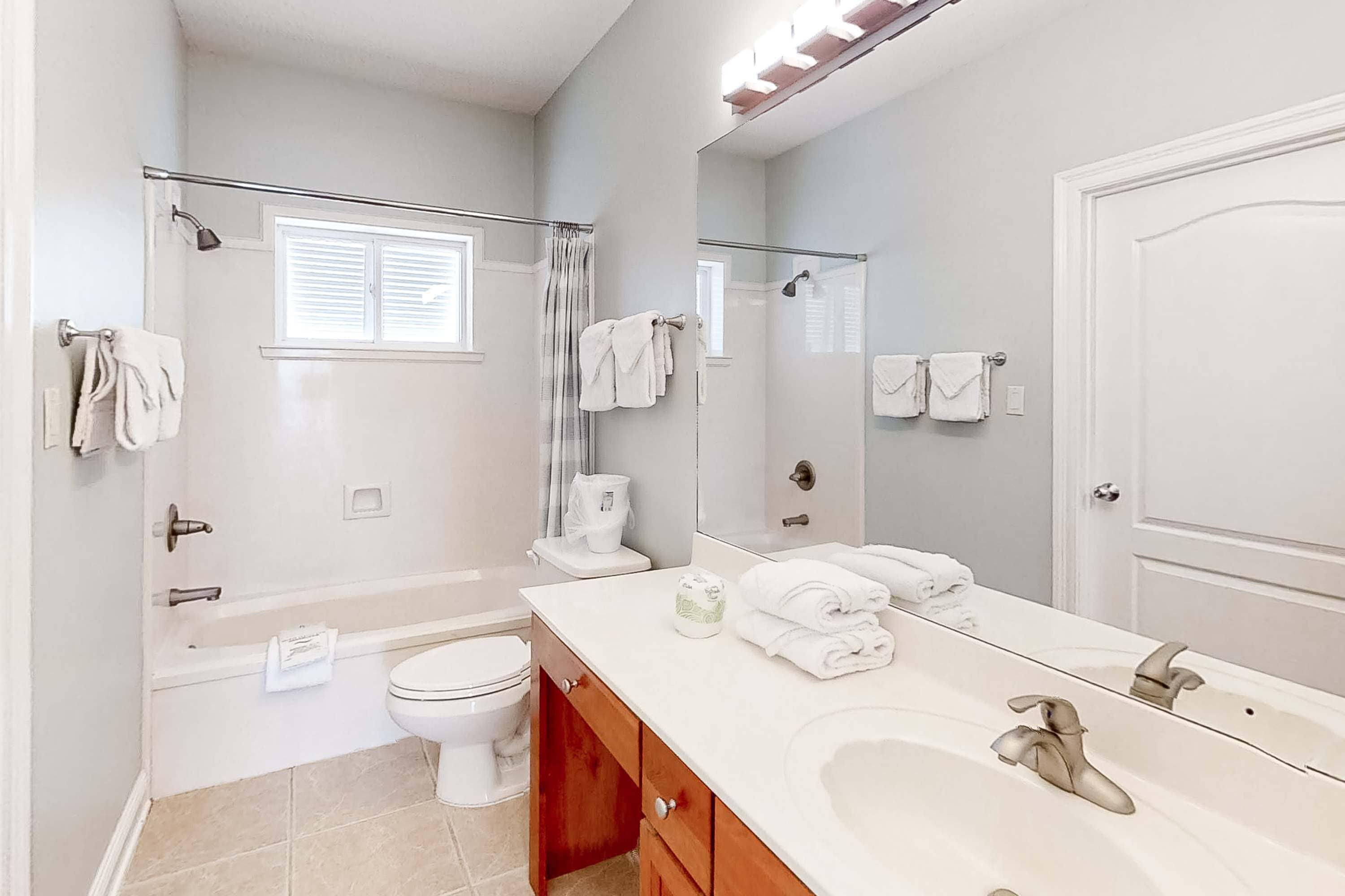 A modern bathroom with a bathtub, toilet, and a large mirror.