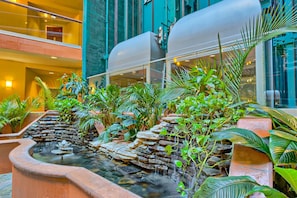 A multi-level atrium with a water feature, indoor plants, and a modern building facade. - Beachfront 13th-floor condo with balcony, hot tubs, pools, & tennis courts (Orange Beach)