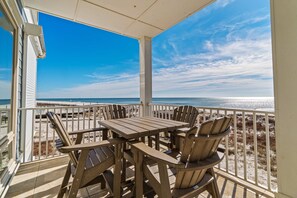 A wooden deck with a table and chairs, overlooking a beach with a railing. - Spacious beachfront wedding-friendly home with multiple decks & shared pool (Orange Beach)