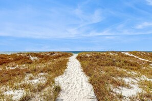 A sandy path leading to a beach with dunes on either side. - Spacious beachfront wedding-friendly home with multiple decks & shared pool (Orange Beach)
