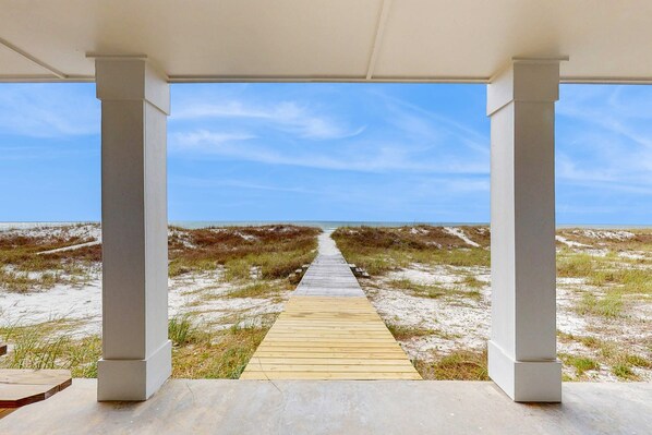 A wooden pathway leading to a beach with white columns and a clear sky. - Spacious beachfront wedding-friendly home with multiple decks & shared pool (Orange Beach)