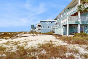 A beachfront property with multiple-story buildings, a sandy beach, and a clear sky. - Spacious beachfront wedding-friendly home with multiple decks & shared pool (Orange Beach)