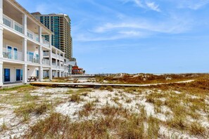 A beachfront hotel with multiple balconies, a sandy beach, and a boardwalk. - Spacious beachfront wedding-friendly home with multiple decks & shared pool (Orange Beach)