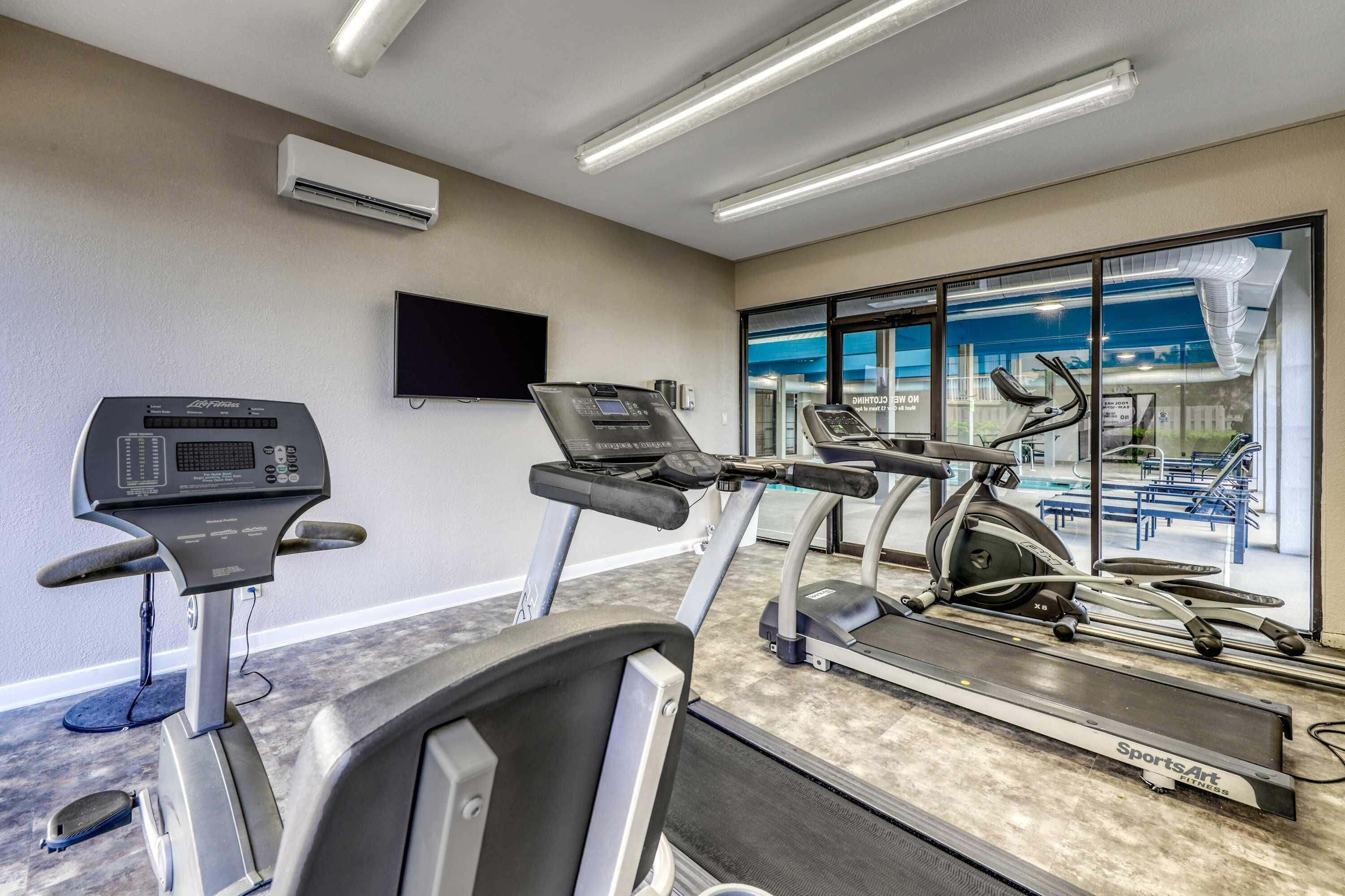 A gym with treadmills, stationary bikes, and a rowing machine.