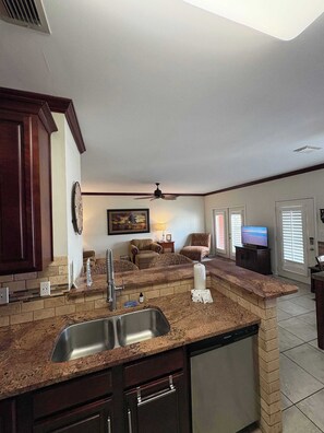 A kitchen with granite countertops, a built-in dishwasher, and a dining area with a table and chairs. - Ground-Floor Condo near the Beach w/Private Patio, Shared Pool, and Central A/C (Orange Beach)