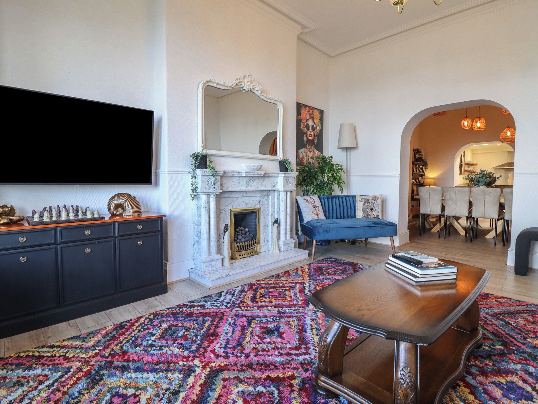 Un salon avec une cheminée, un canapé bleu, une table basse et un téléviseur fixé au mur.