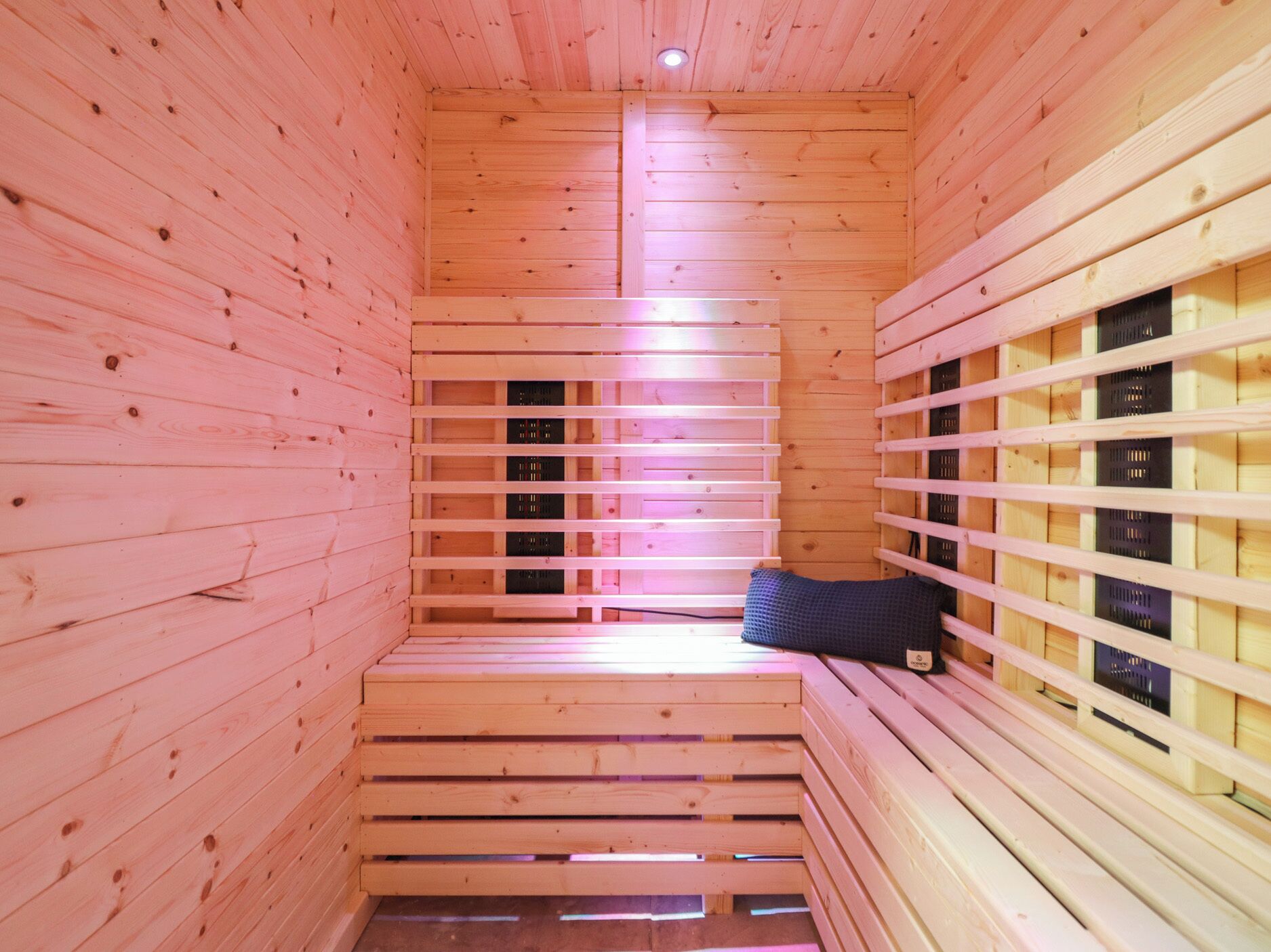 A sauna with wooden walls and benches, a bench with a towel, and a window with a view.