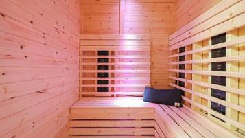 A sauna with wooden walls and benches, a bench with a towel, and a window with a view.
