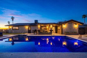 Uma casa moderna com piscina, área de estar ao ar livre e um pátio bem iluminado.