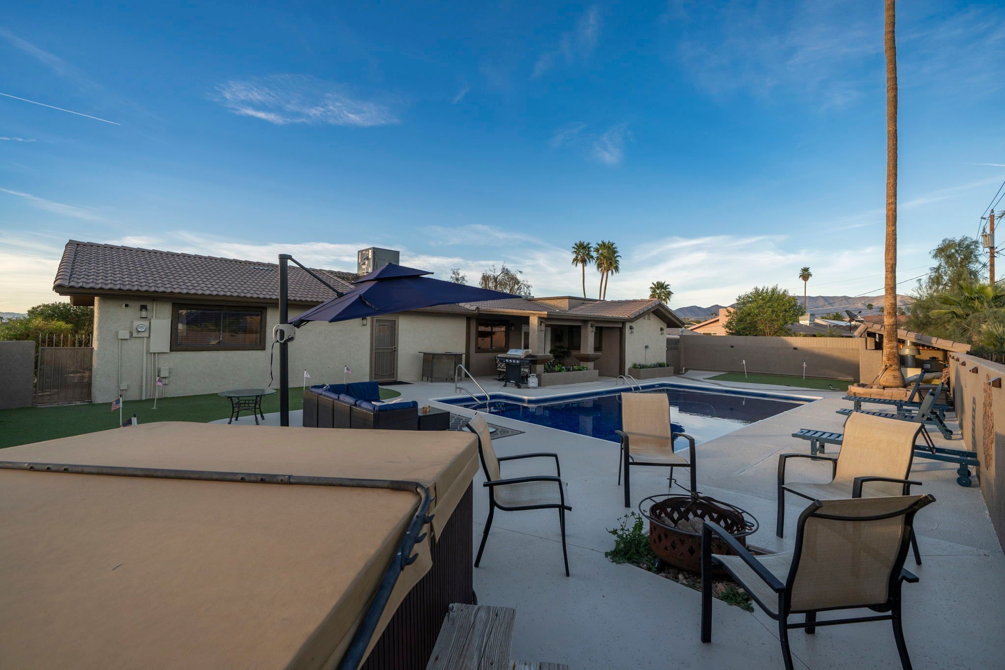 A backyard with a swimming pool, outdoor furniture, and a covered seating area.