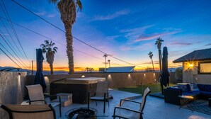 Un patio al aire libre con asientos, una fogata y vistas al atardecer.