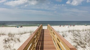 A wooden boardwalk leading to a beach with umbrellas and people. - Luxury Gulf-front home w private splash pool & direct beach access (Orange Beach)