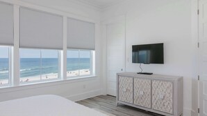 A bedroom with a large window, a bed, a TV, and a cabinet. - Luxury Gulf-front home w private splash pool & direct beach access (Orange Beach)