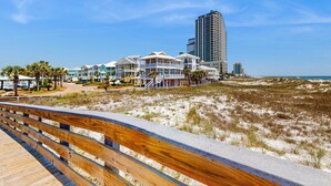 Een hotel aan het strand met meerdere gebouwen, een houten promenade en een zandstrand.