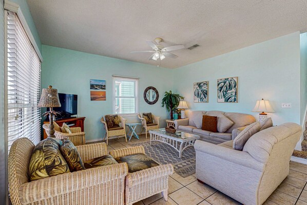 A living room with wicker furniture, a ceiling fan, and a television. - Family-friendly beach home w Gulf views, a full kitchen, & spacious living area (Orange Beach)