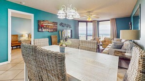 A spacious living room with a large dining table, wicker furniture, a ceiling fan, and a view to the outside. - Waterfront condo w/ balcony, multiple pools, lighted tennis courts, hot tub (Orange Beach)