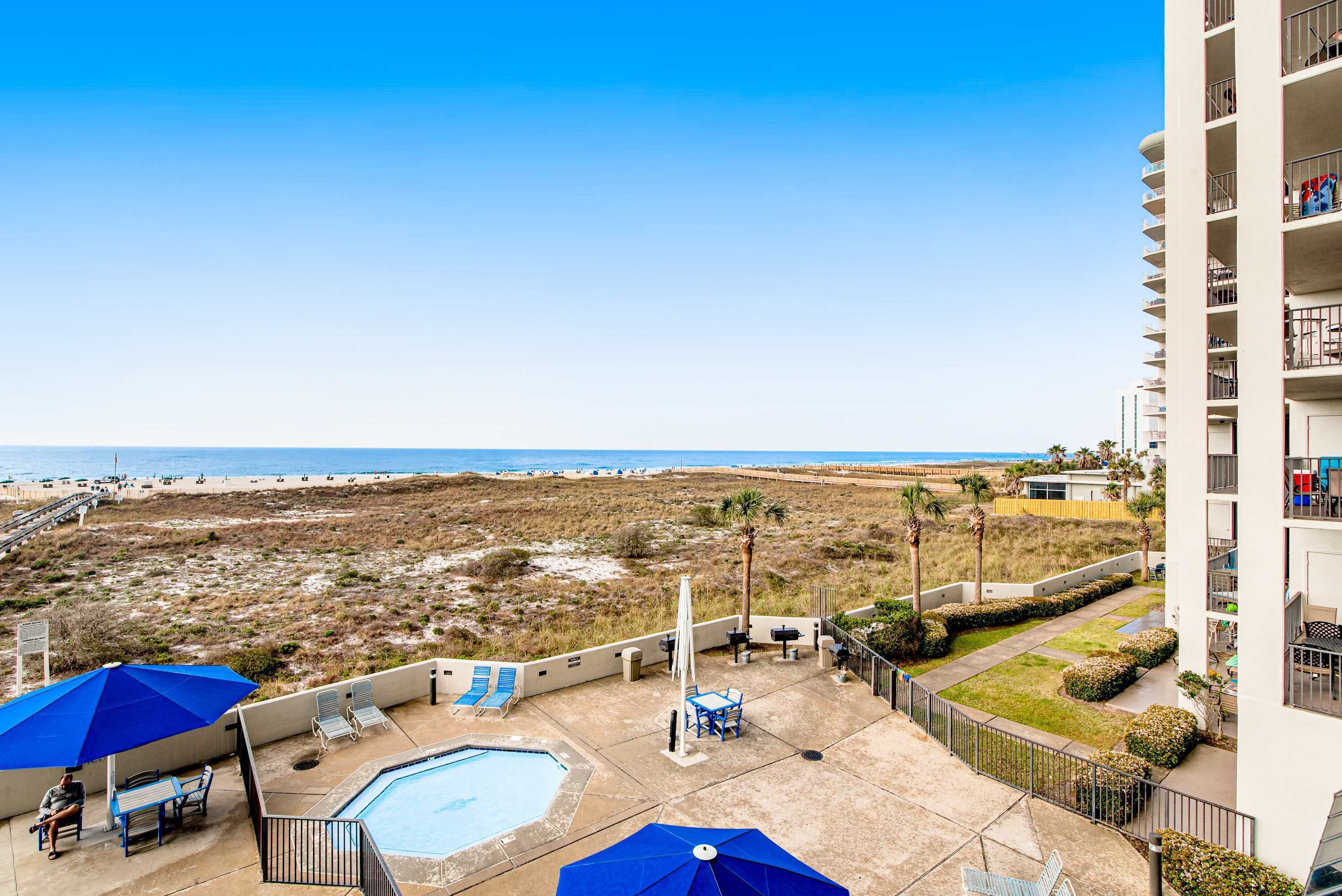 Ein Hotel mit Pool, Sitzgelegenheiten im Freien und Blick auf den Strand.