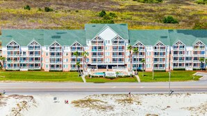 Een hotel aan het strand met meerdere balkons, een zwembad en een groen gazon.