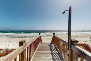 A wooden boardwalk leading to a beach with waves and a clear sky. - Delightful escape with direct beach access, WiFi, furnished deck, & full kitchen (Gulf Shores)