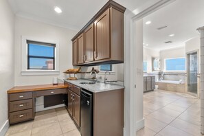 A modern kitchen with wooden cabinets, a built-in dishwasher, and a window with blinds. - Delightful escape with direct beach access, WiFi, furnished deck, & full kitchen (Gulf Shores)