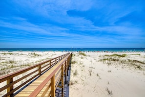 A wooden boardwalk leading to a beach with sand dunes and a clear blue sky. - Ocean-view condo with central AC, indoor pool, & gym - sunsets on the beach (Gulf Shores)