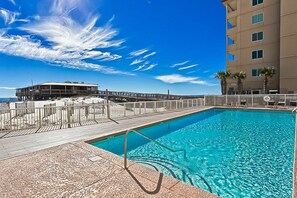 A swimming pool with a wooden deck and a building in the background. - Boardwalk 283 gulf-view condo with WiFi, central ac, balcony, & outdoor pool (Gulf Shores)