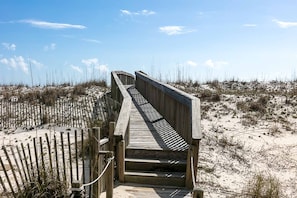 A wooden boardwalk leading to a sandy beach area with sparse vegetation. - Direct Lagoon Front Home w/ Shared Pool, Free WiFi, Central A/C, & Water Views (Gulf Shores)