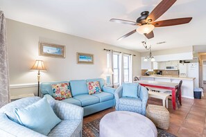 A living room with a sofa, armchairs, a ceiling fan, and a kitchen area in the background. - Direct Lagoon Front Home w/ Shared Pool, Free WiFi, Central A/C, & Water Views (Gulf Shores)