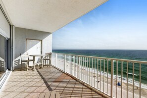 Ein Balkon mit Blick auf den Strand, einem Tisch und Stühlen.