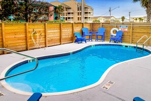A swimming pool with blue chairs, a no lifeguard warning sign, and a wooden fence. - Gorgeous Condo in Beachfront Location w/Shared Pool, Central AC, Free WiFi (Gulf Shores)