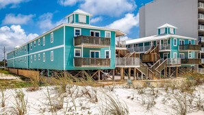 Ett hotell vid stranden med flera våningar, träbalkonger och en sandstrand framför.