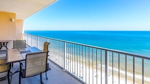 Ein Balkon mit Meerblick, einem Tisch, Stühlen und einem Geländer.