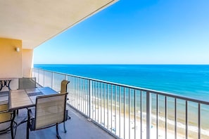 A balcony with a view of the ocean, a table, chairs, and a railing. - Gulf-front penthouse with pool, sauna, washer,dryer, & central AC (Gulf Shores)