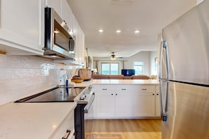 A modern kitchen with white cabinetry, stainless steel appliances, and a central island. - Multi-Level, Beachfront Condo w/ Gulf Views, Deck, WiFi, AC & Shared Pool (Gulf Shores)