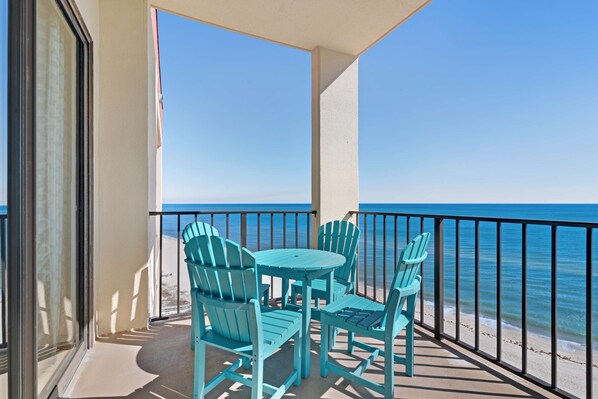 A balcony with a table and chairs, a view of the ocean, and a railing. - Casual beachfront getaway with pool, ocean views, & beach access (Orange Beach)