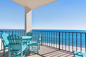 A balcony with a view of the ocean, featuring a table and chairs. - Casual beachfront getaway with pool, ocean views, & beach access (Orange Beach)