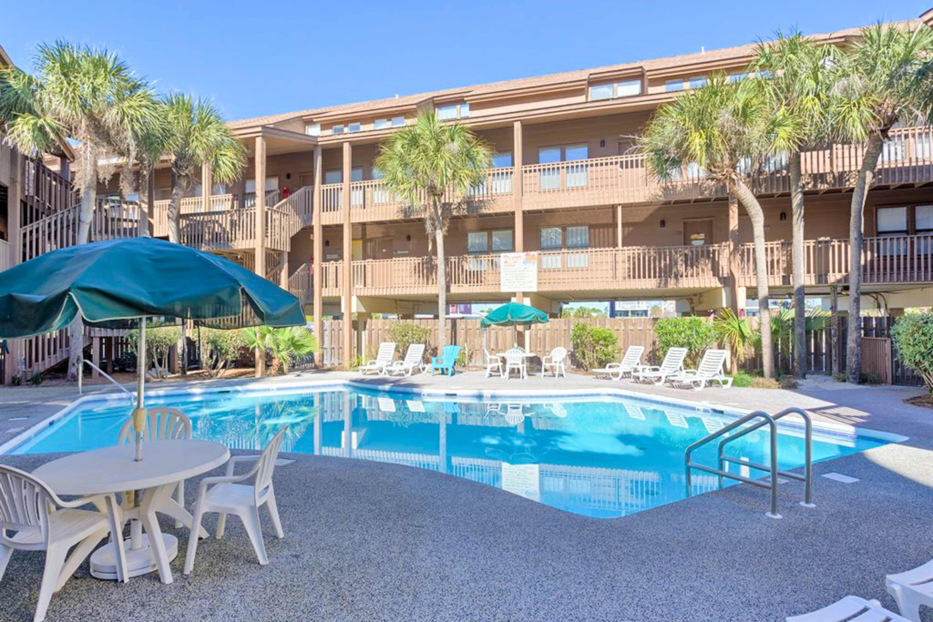Un hotel con piscina, mobiliario exterior y palmeras.