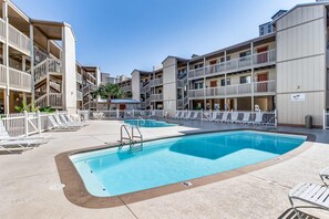 A hotel with a swimming pool, multiple balconies, and a fenced pool area. - Lakeview Condo with Shared Pool - Just Steps from the Beach! (Gulf Shores)