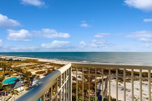 A beach view from a balcony with a pool, beach chairs, and a boardwalk. - Coastal condo with beach access, pool, sauna, and tennis courts (Gulf Shores)