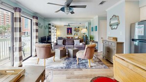 A modern living room with a sofa, armchairs, a coffee table, and a ceiling fan. - Coastal condo close to the beach with balcony - walk everywhere! (Gulf Shores)