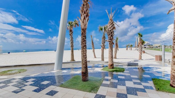 A paved area with palm trees, a checkered pattern, and a view of the beach. - Coastal condo close to the beach with balcony - walk everywhere! (Gulf Shores)
