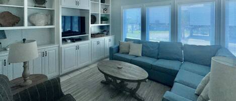 A living room with a blue sofa, a coffee table, and white cabinets.